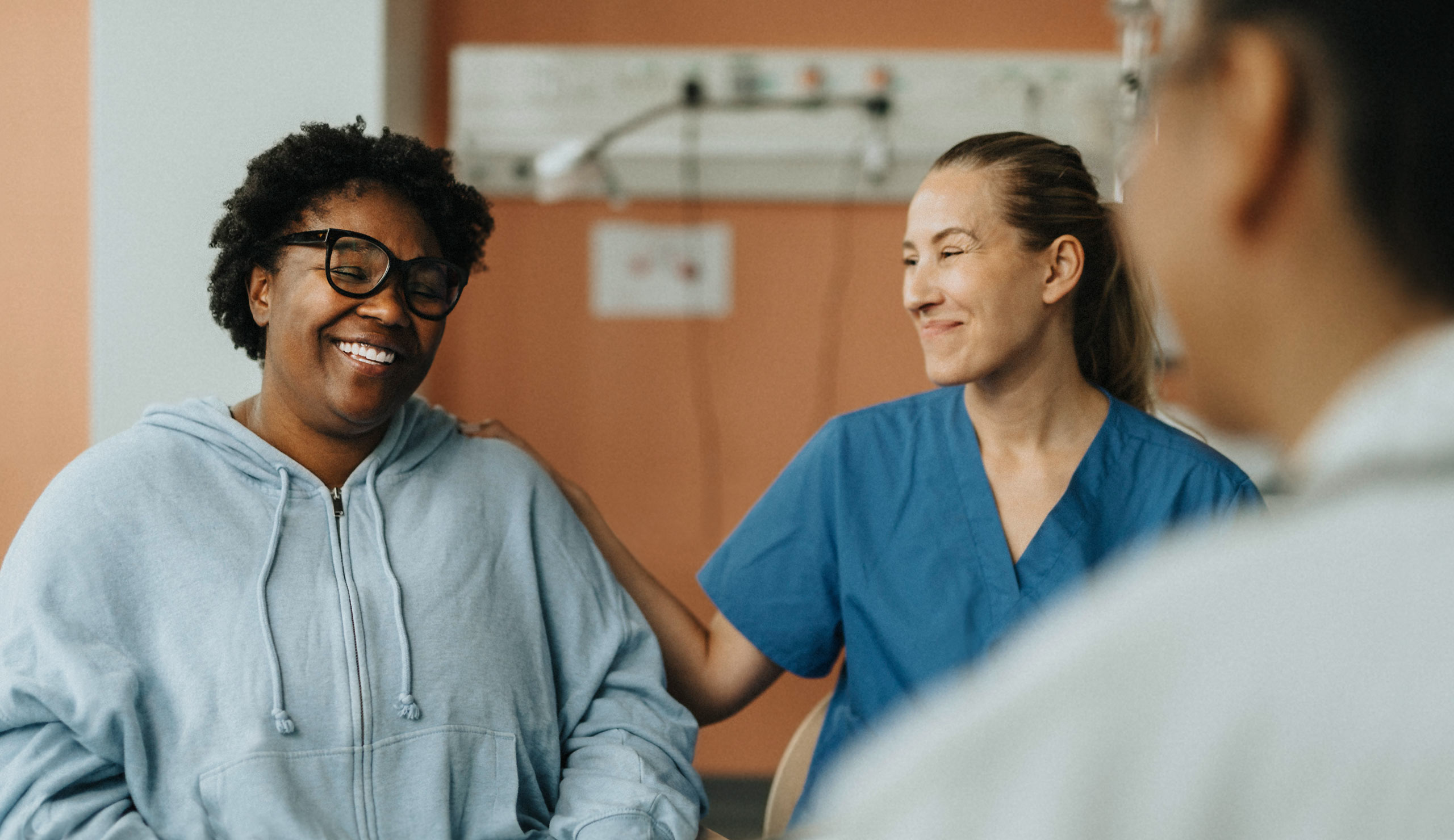 A female patient feeling relieved speaking with a nurse and doctor.